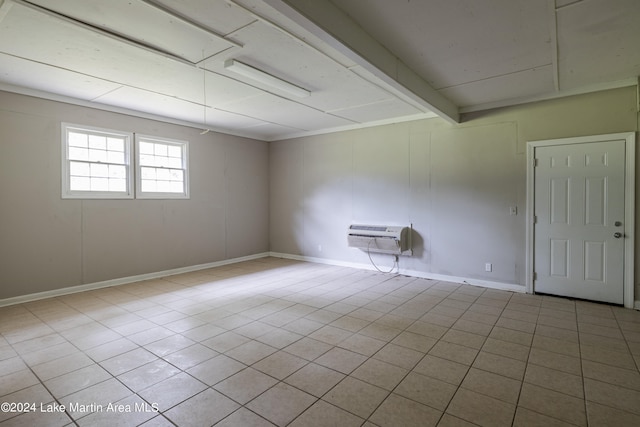 tiled spare room featuring beam ceiling and an AC wall unit