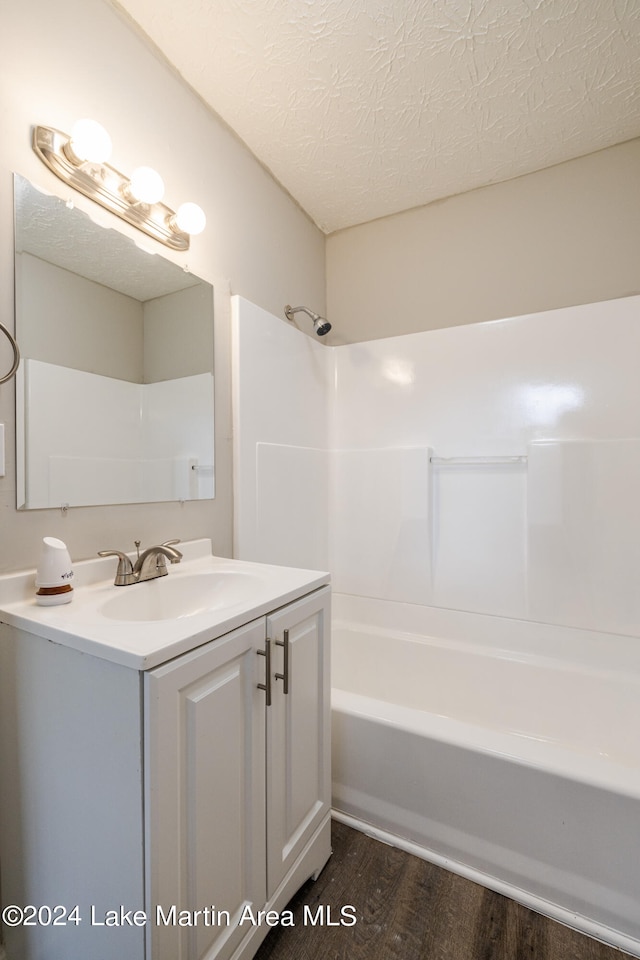 bathroom with shower / bath combination, vanity, wood-type flooring, and a textured ceiling