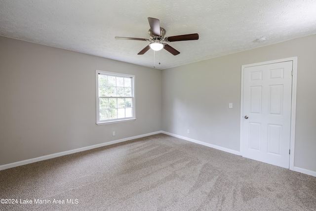 unfurnished room with a textured ceiling, carpet floors, and ceiling fan