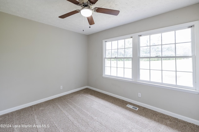 carpeted empty room featuring ceiling fan and a textured ceiling