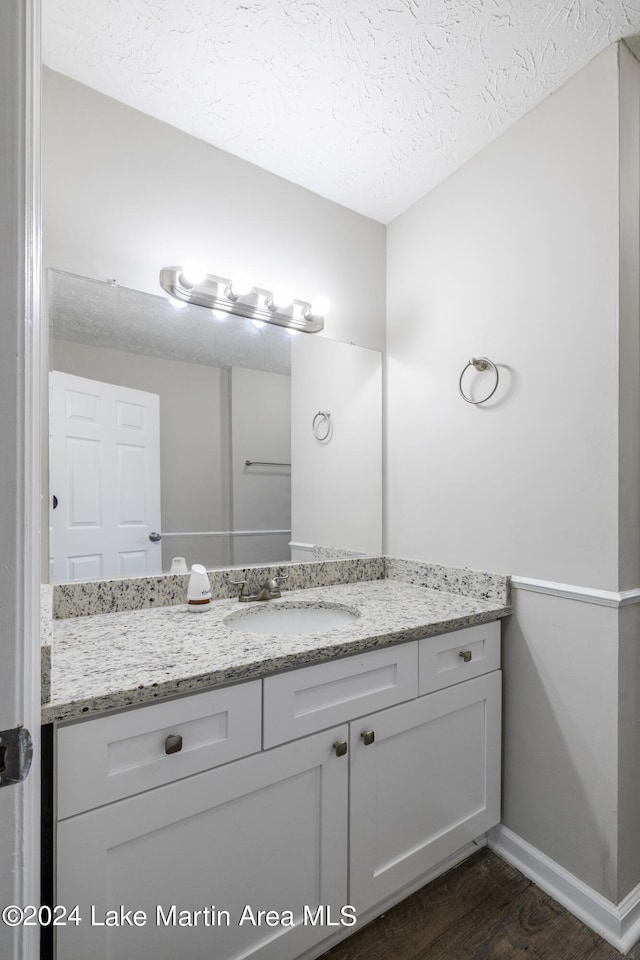 bathroom with vanity, wood-type flooring, and a textured ceiling