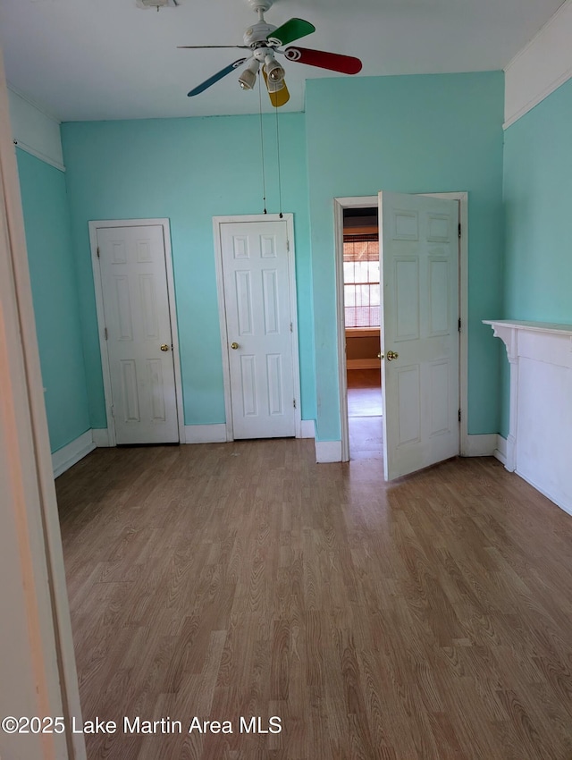 311 John St, Tallassee, AL 36078 - unfurnished bedroom featuring two closets, baseboards, a ceiling fan, and wood finished floors
