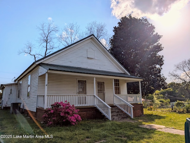 311 John St, Tallassee, AL 36078 - view of front of property featuring covered porch, a front yard, and metal roof