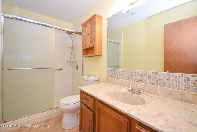 bathroom featuring tasteful backsplash, tile patterned floors, walk in shower, vanity, and toilet