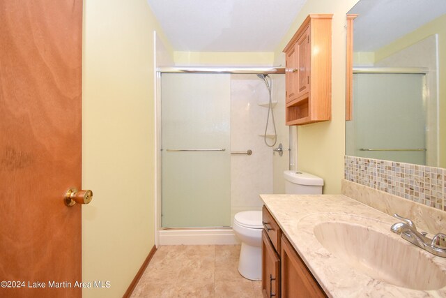 bathroom with vanity, backsplash, tile patterned floors, toilet, and a shower with shower door