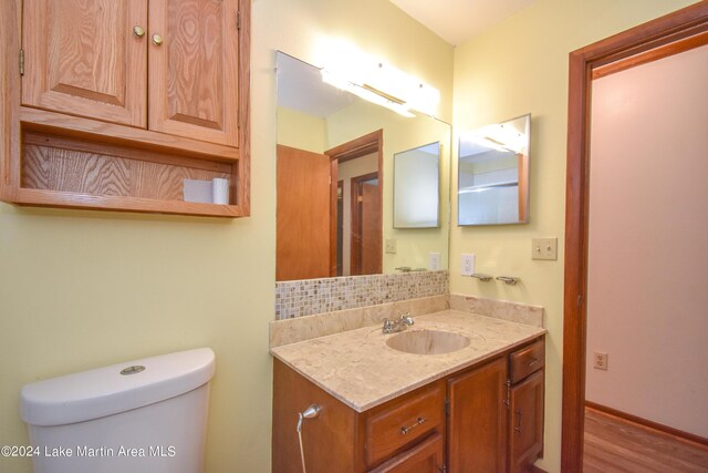 bathroom with hardwood / wood-style floors, vanity, and toilet