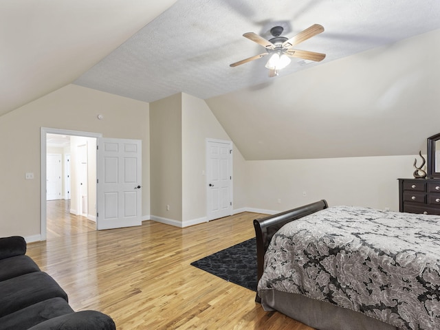 bedroom with a textured ceiling, ceiling fan, lofted ceiling, and light wood-type flooring