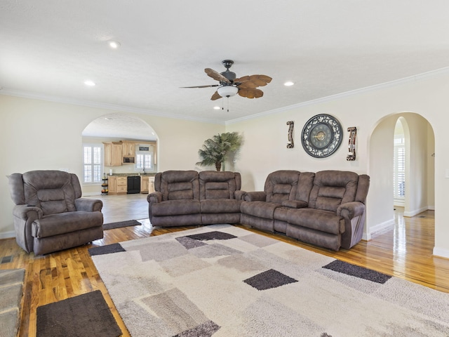 living room with light hardwood / wood-style floors, ceiling fan, and ornamental molding