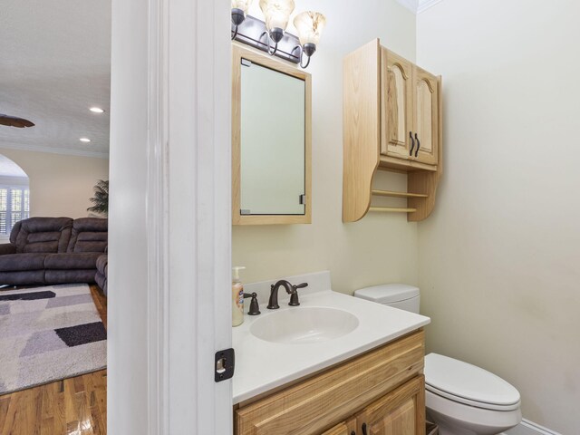 bathroom with crown molding, toilet, vanity, and hardwood / wood-style flooring