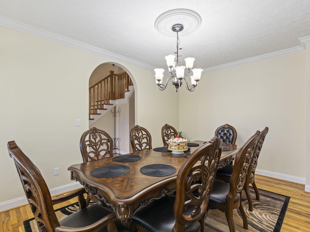 dining space featuring ornamental molding, light hardwood / wood-style flooring, and a notable chandelier