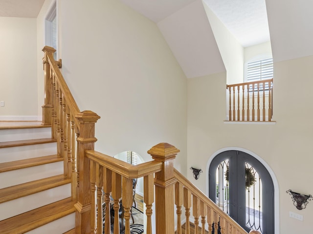 stairs featuring french doors and lofted ceiling