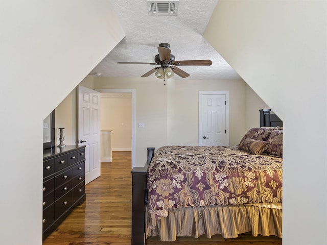 bedroom with a textured ceiling, dark hardwood / wood-style floors, and ceiling fan