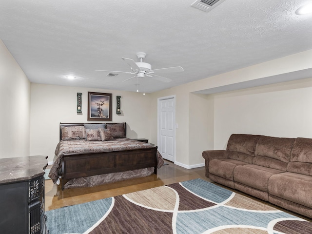 bedroom with ceiling fan, hardwood / wood-style floors, and a textured ceiling