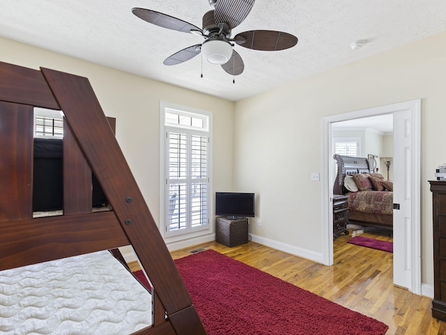 bedroom featuring a textured ceiling, light hardwood / wood-style floors, multiple windows, and ceiling fan