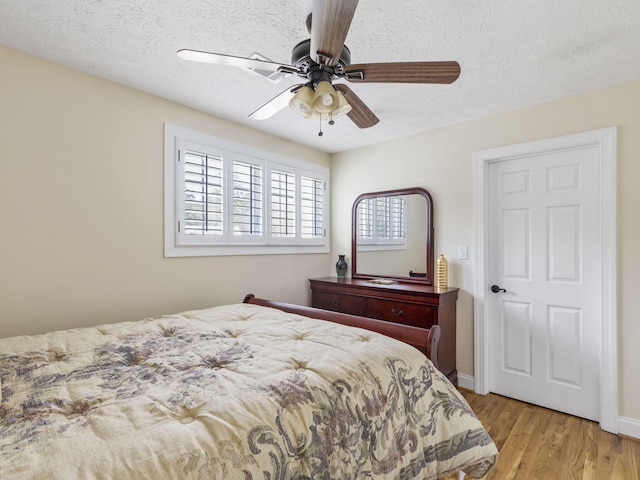 bedroom featuring ceiling fan, light wood-type flooring, and a textured ceiling