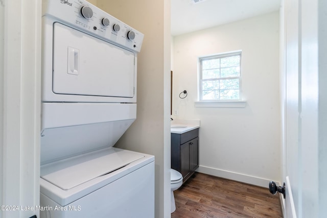 laundry room featuring stacked washer and dryer, dark wood-type flooring, and sink