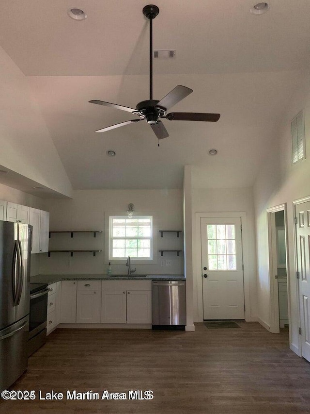 kitchen with vaulted ceiling, appliances with stainless steel finishes, sink, white cabinets, and dark hardwood / wood-style floors