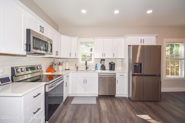 kitchen with white cabinets, sink, dark hardwood / wood-style floors, decorative backsplash, and appliances with stainless steel finishes