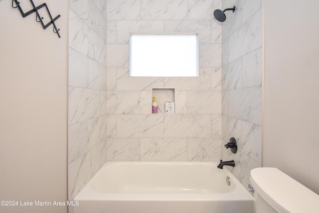 bathroom featuring tiled shower / bath combo and toilet