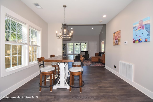 dining area featuring lofted ceiling, dark hardwood / wood-style floors, and an inviting chandelier