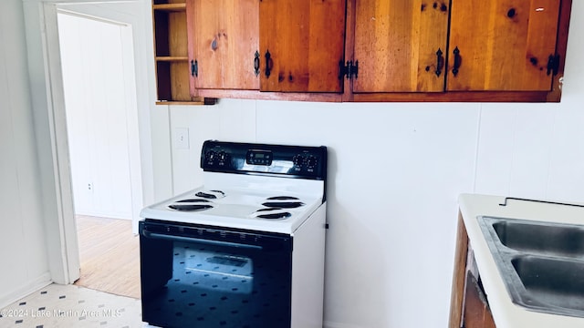 kitchen with electric stove, sink, and light hardwood / wood-style flooring