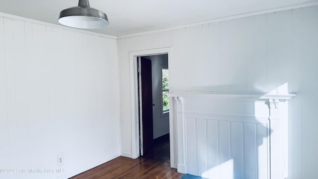 spare room with wood walls, ornamental molding, and dark wood-type flooring