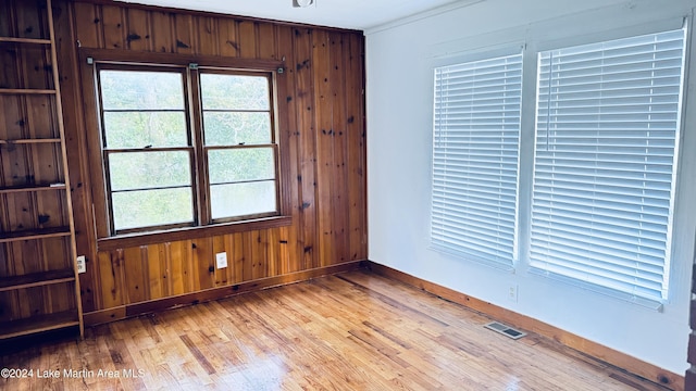 spare room featuring wood walls and light hardwood / wood-style flooring