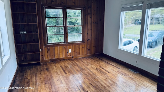 spare room with wooden walls and wood-type flooring