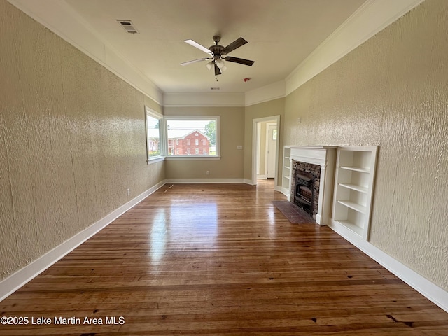 104 Central Blvd, East Tallassee, AL 36078 - unfurnished living room with hardwood / wood-style floors, a ceiling fan, a stone fireplace, a textured wall, and ornamental molding