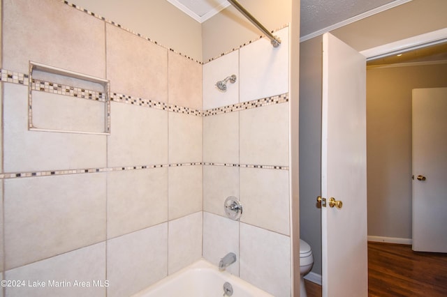 bathroom featuring hardwood / wood-style floors, toilet, ornamental molding, and tiled shower / bath