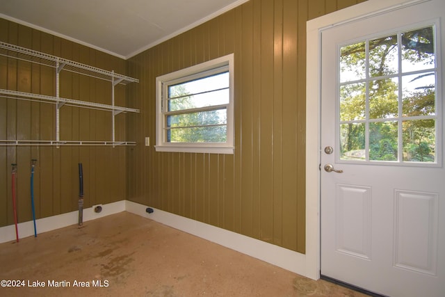 laundry area featuring crown molding and wood walls