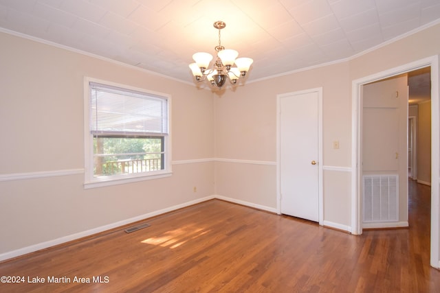 spare room featuring a chandelier, ornamental molding, and dark wood-type flooring