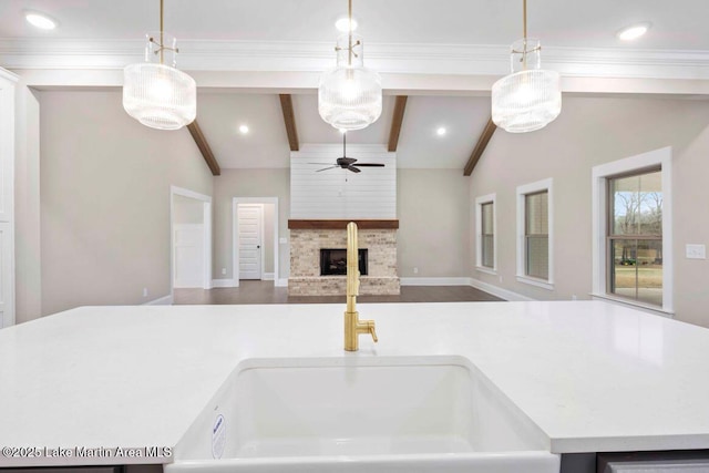 kitchen featuring lofted ceiling with beams, ceiling fan, a fireplace, and decorative light fixtures