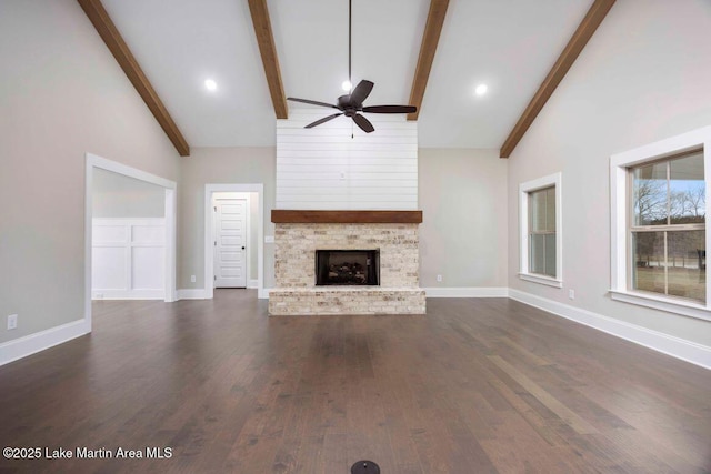 unfurnished living room with dark wood-type flooring, ceiling fan, beam ceiling, high vaulted ceiling, and a fireplace