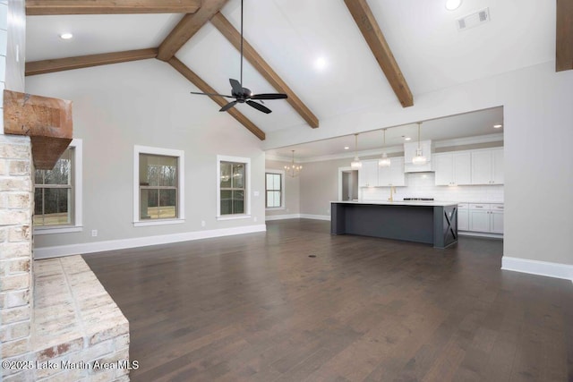 unfurnished living room featuring dark hardwood / wood-style flooring, ceiling fan with notable chandelier, high vaulted ceiling, and beamed ceiling