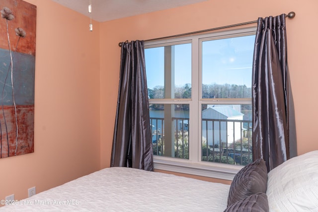 bedroom with a water view and multiple windows