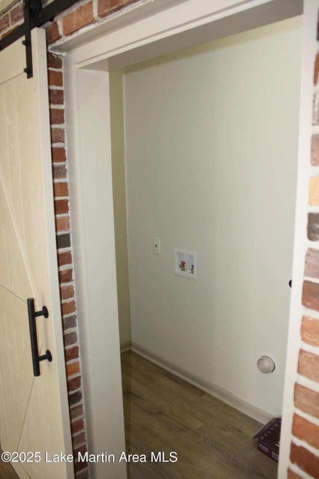 laundry room with dark wood-style floors, hookup for a washing machine, a barn door, laundry area, and baseboards