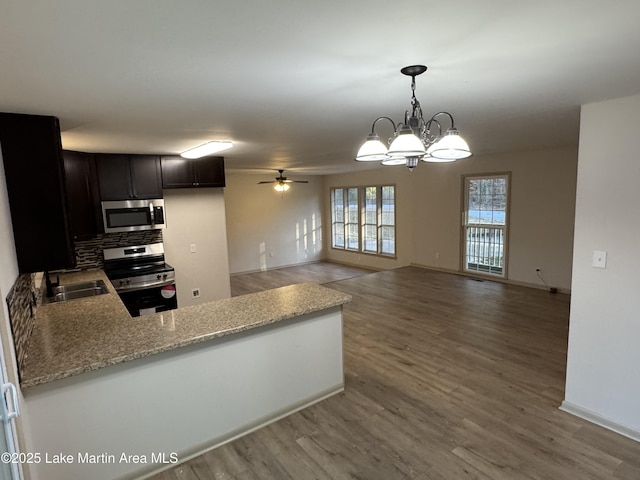 kitchen featuring sink, appliances with stainless steel finishes, hanging light fixtures, hardwood / wood-style floors, and kitchen peninsula