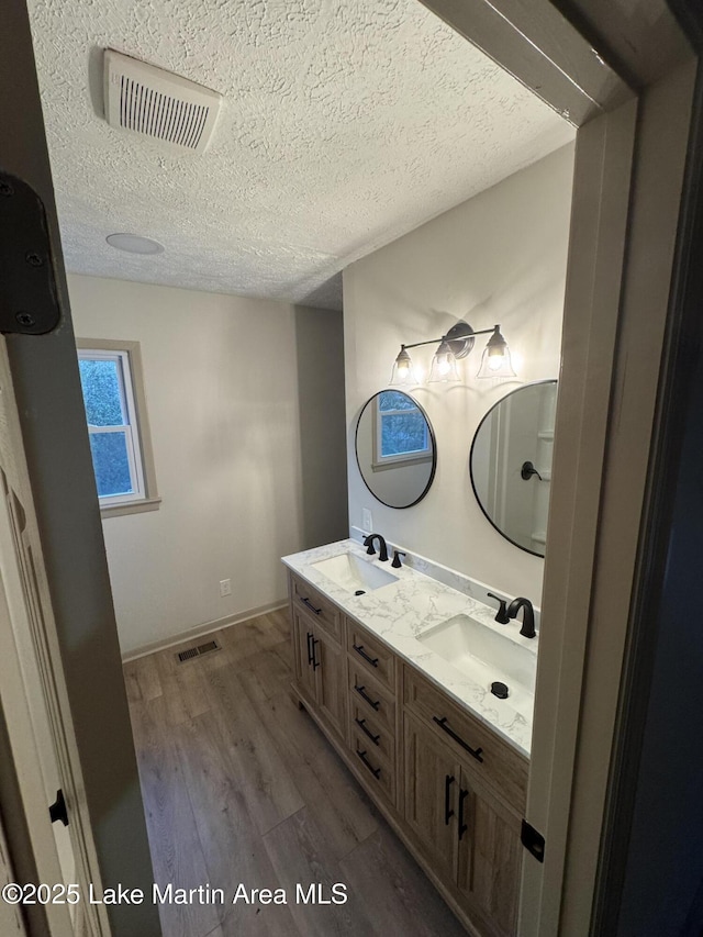 bathroom with hardwood / wood-style flooring, vanity, and a textured ceiling