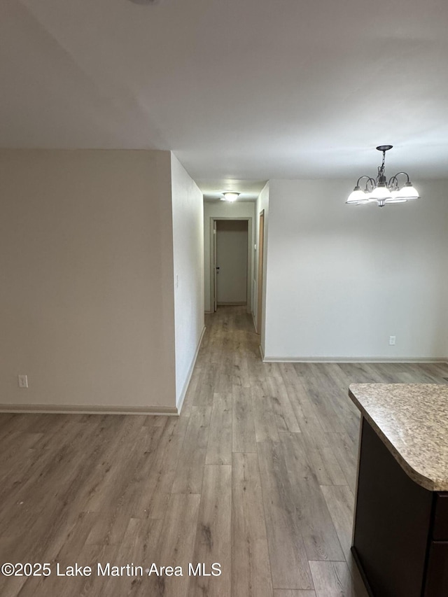 hallway with an inviting chandelier and light wood-type flooring