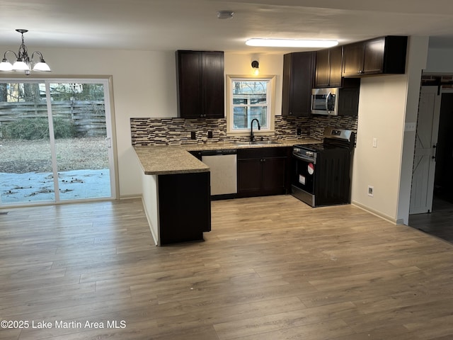 kitchen with sink, light hardwood / wood-style flooring, hanging light fixtures, stainless steel appliances, and tasteful backsplash