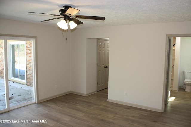 empty room with a ceiling fan, a textured ceiling, baseboards, and wood finished floors