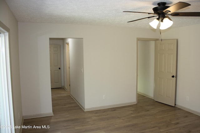 empty room with a textured ceiling, baseboards, and wood finished floors