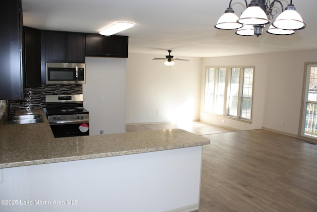 kitchen with stainless steel appliances, open floor plan, hanging light fixtures, and a peninsula