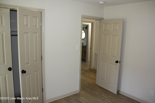 hall featuring baseboards, visible vents, and light wood-style floors