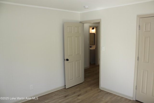 unfurnished room featuring baseboards, wood finished floors, and crown molding