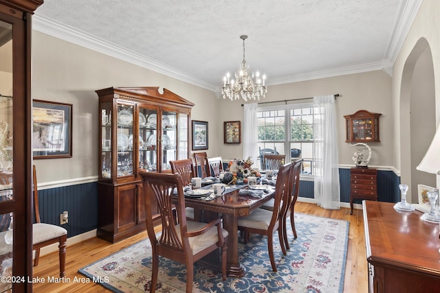 dining room featuring a chandelier, crown molding, light hardwood / wood-style floors, and a textured ceiling