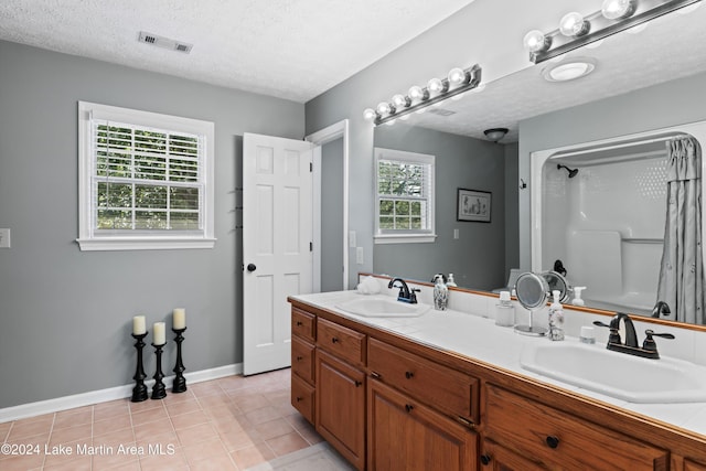 bathroom with vanity, a textured ceiling, tile patterned floors, and a wealth of natural light