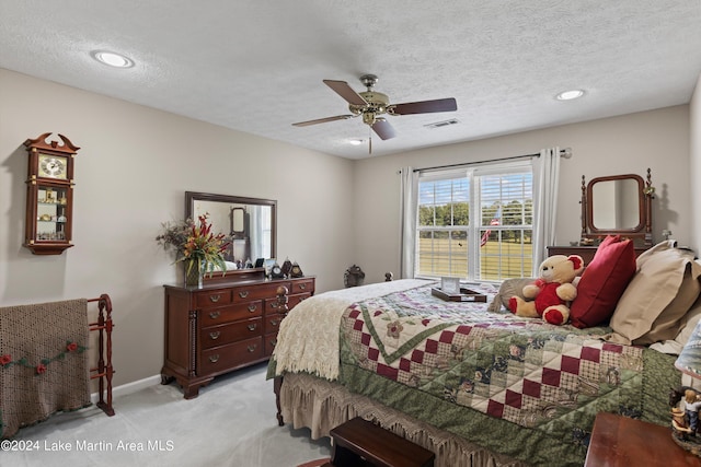 bedroom featuring ceiling fan, light colored carpet, and a textured ceiling