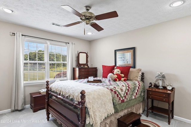 bedroom with ceiling fan, light colored carpet, and a textured ceiling